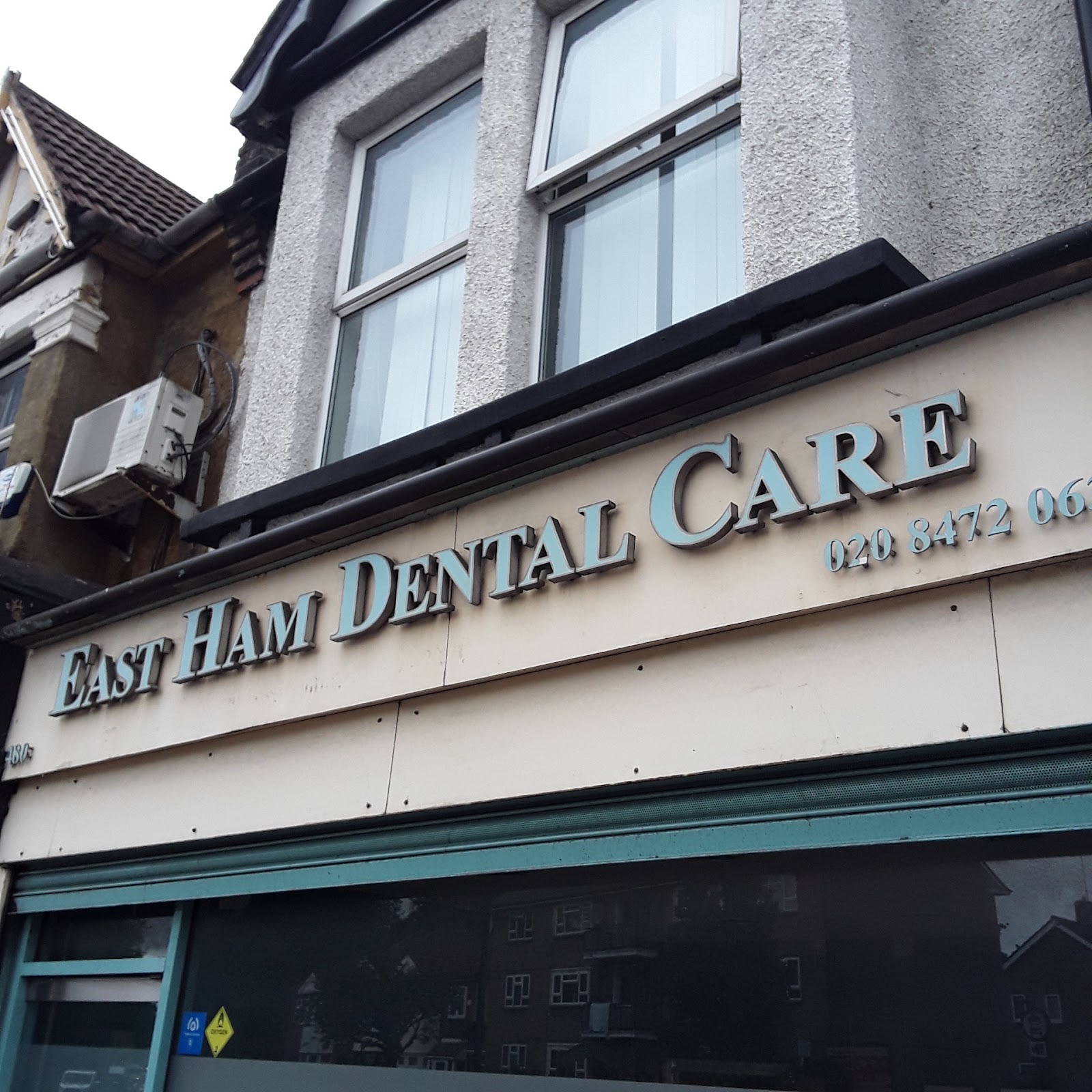 The East Ham Dental Care shopfront sign in teal lettering on Barking Road, East Ham E6